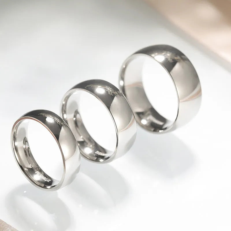 Silver-coloured plain titanium band ring shown in three different widths: 2mm, 4mm, and 6mm.