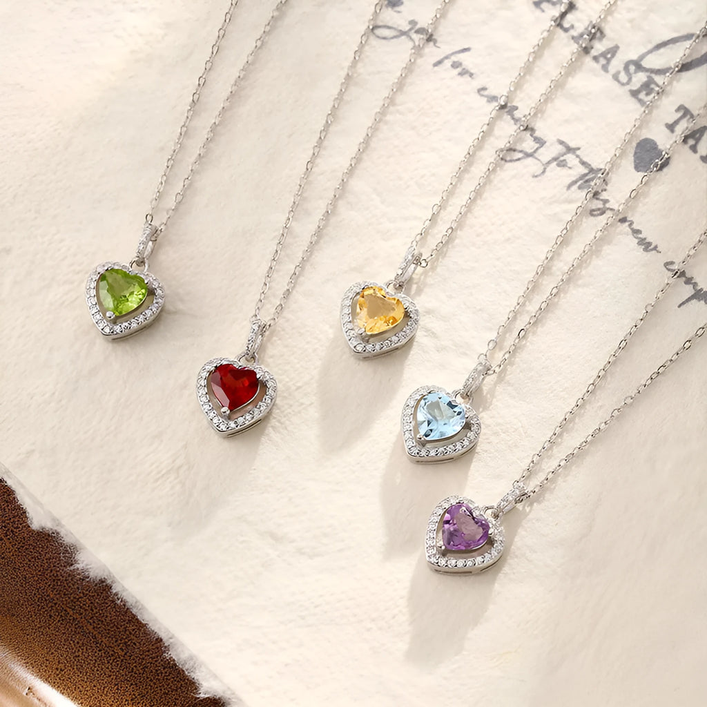 Sterling silver heart pendant necklace with inlaid gemstone on a cross chain, adjustable length.