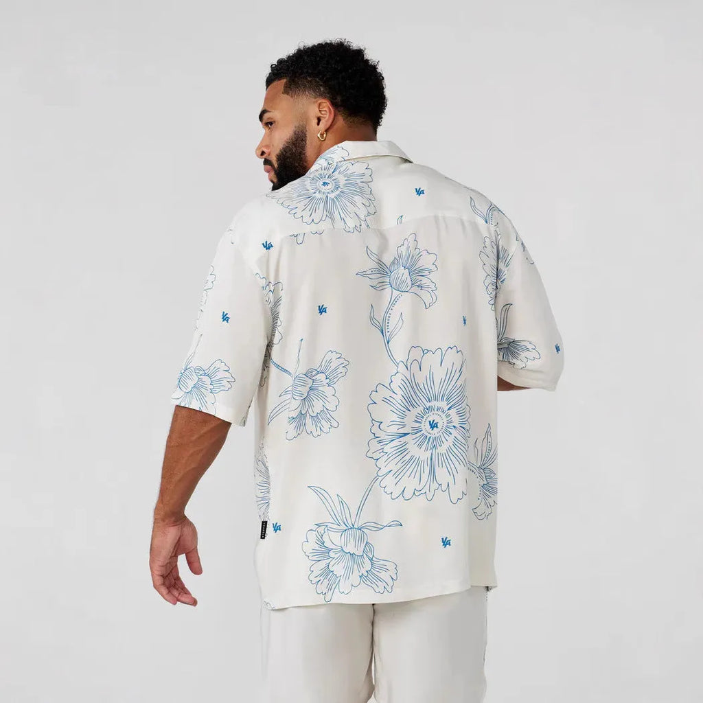 Man wearing a loose, light grey printed short sleeve casual top made from stretch polyester fabric.