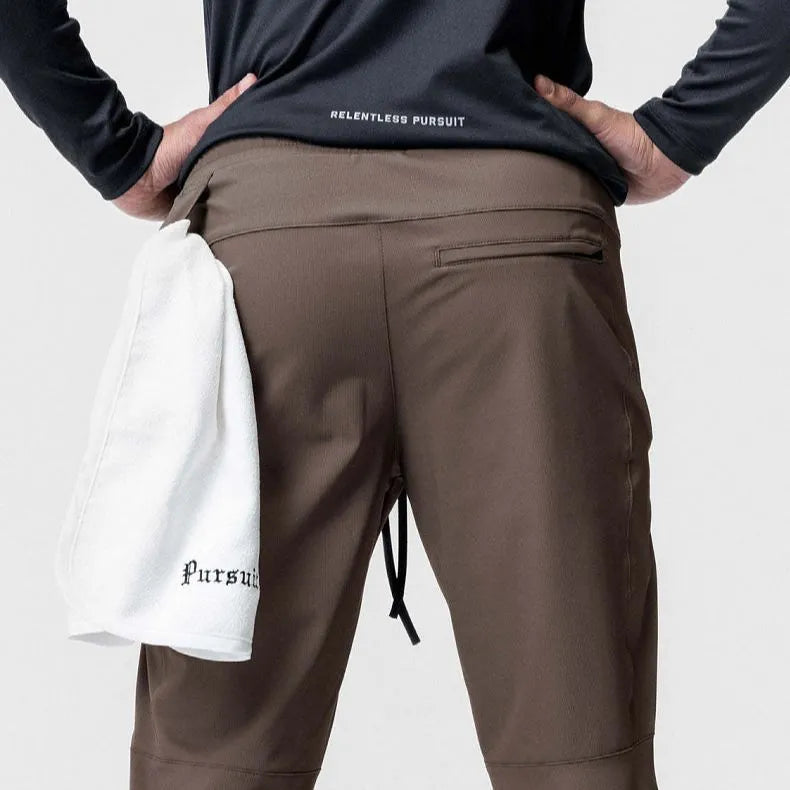 Man wearing dark grey quick-dry fitness trousers with ankle ties, suitable for running and gym workouts.