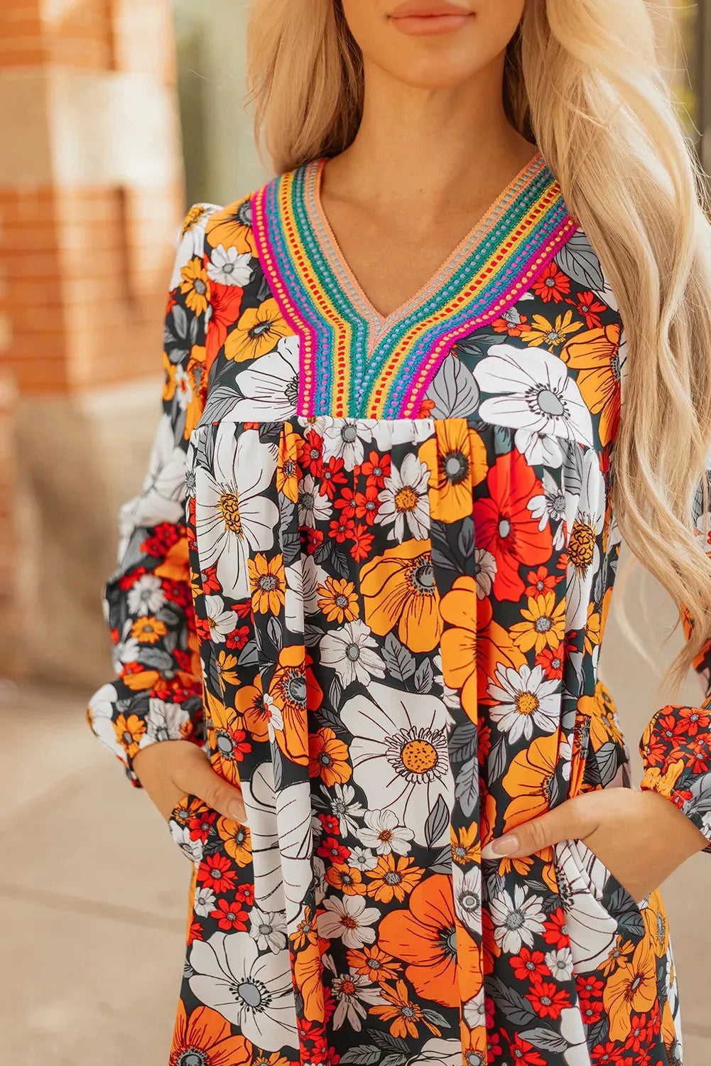 Orange floral and striped patterned mini dress with a lace-trimmed V-neck collar and long sleeves.