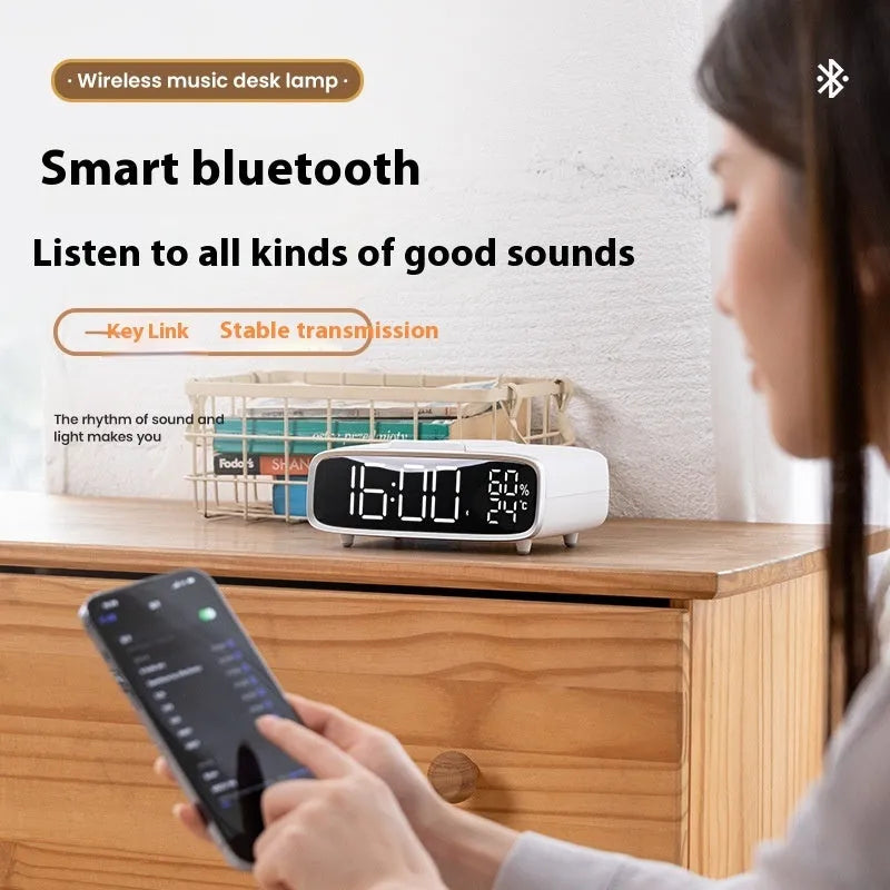 White ABS acrylic Bluetooth speaker wireless charger with night lamp and alarm clock on a desk showing charging pad and speaker grille