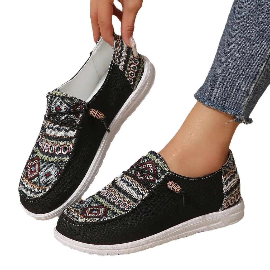 Women's black flat shoes with round toe and slip-on design on neutral background