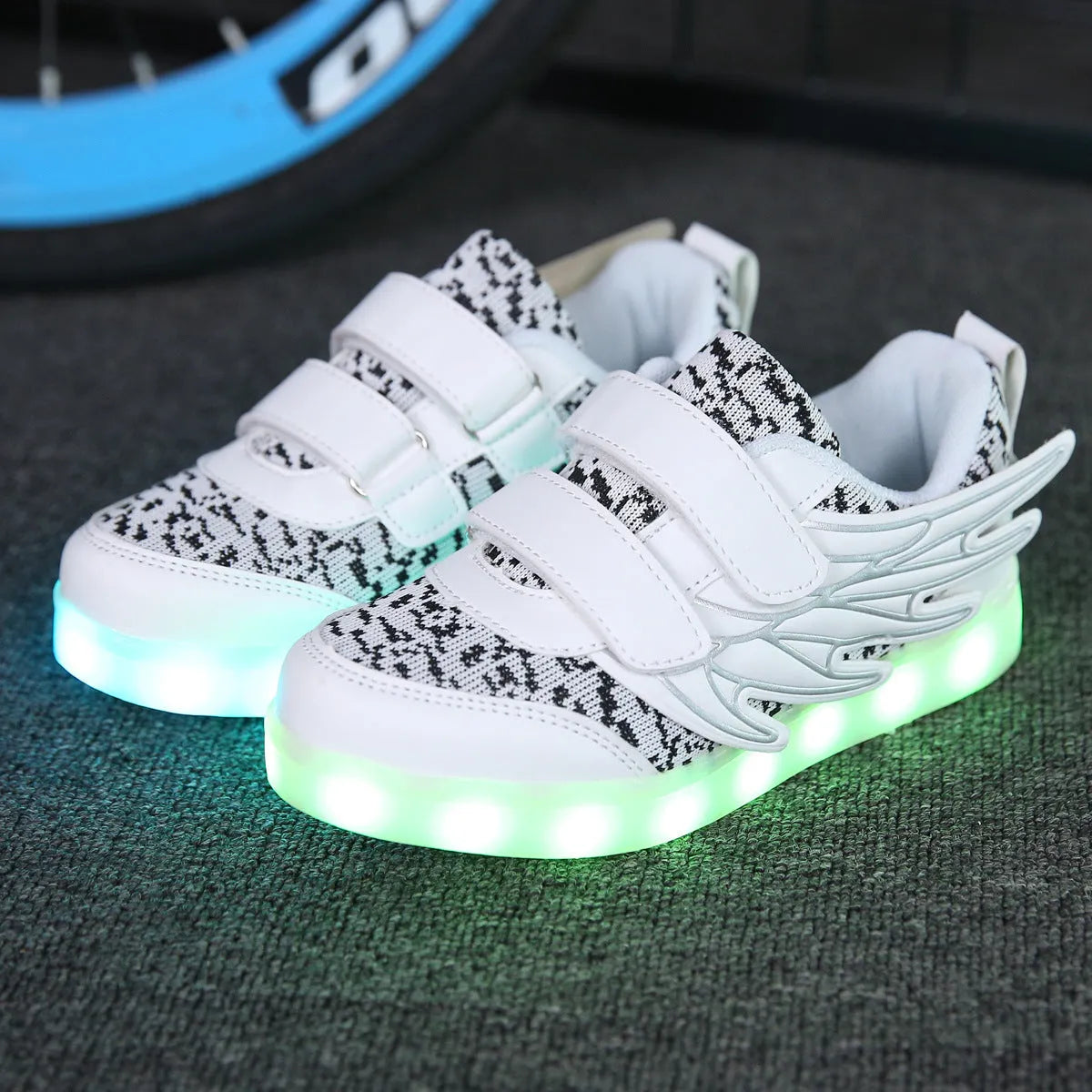 Children's plum red and white sneakers with colourful LED lights glowing on the side.