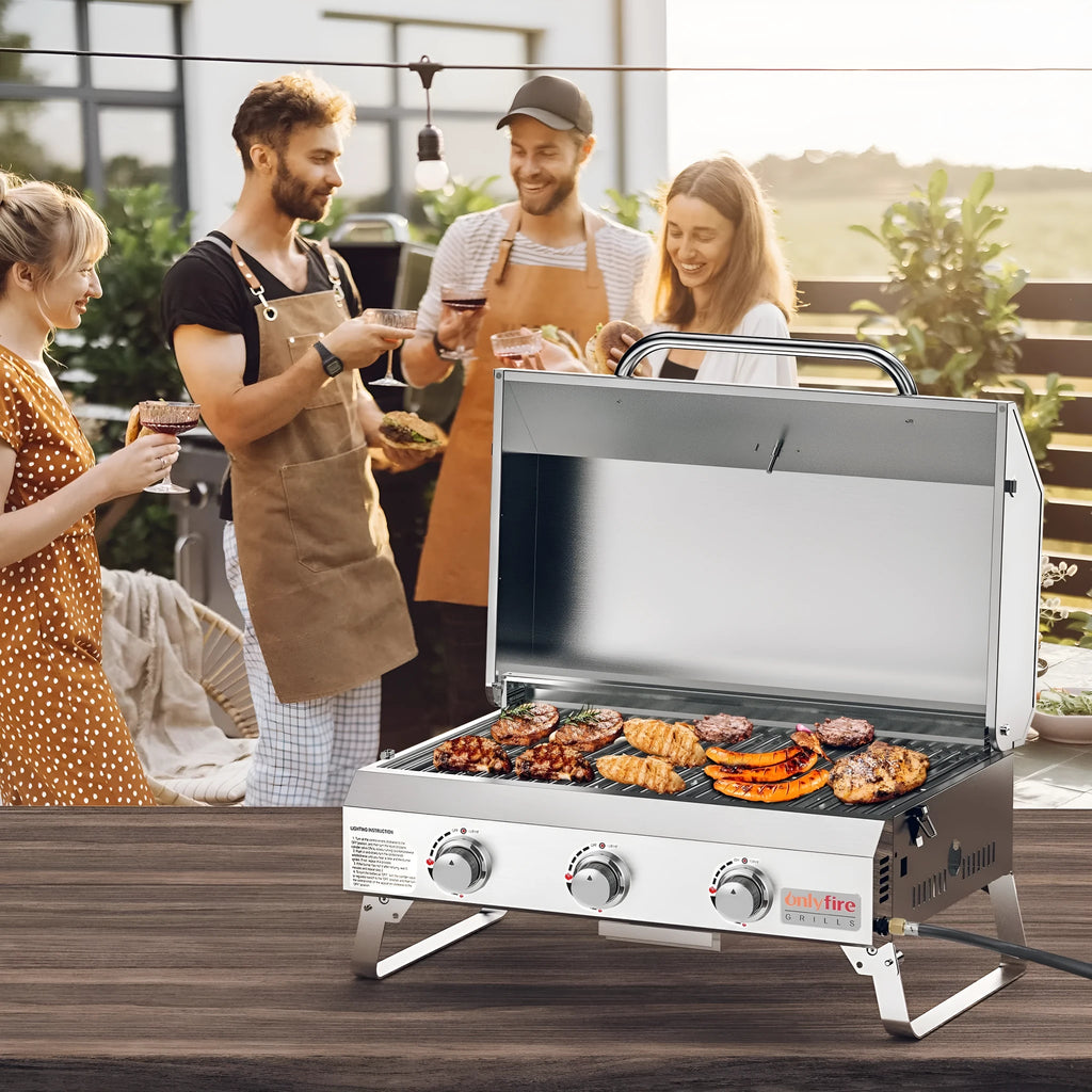 Silver desktop gas barbecue grill with three stainless steel burners and foldable legs