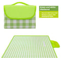 Thickened outdoor picnic mat in green grid non-woven fabric, folded on grass