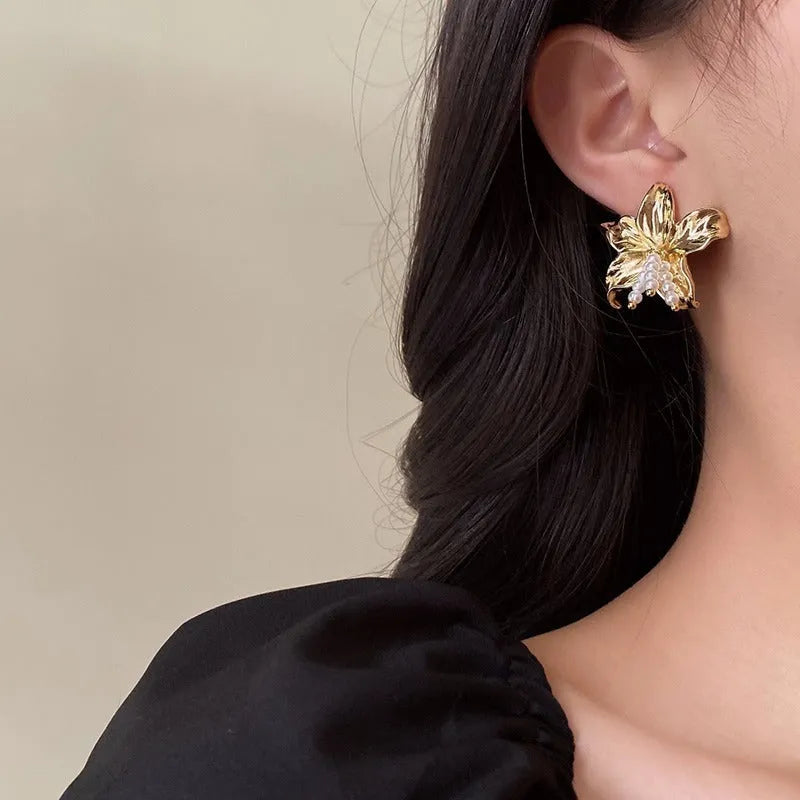 Gold pearl flower earrings with metal post back on white background, exaggerated floral shape