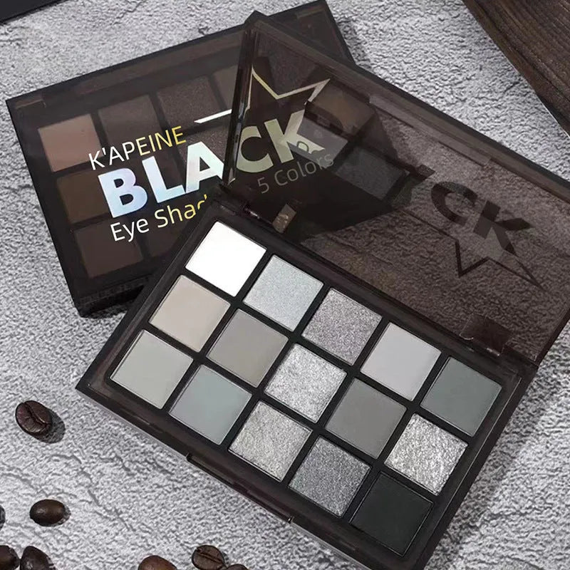 Open 15-colour eyeshadow palette showing matte grey, black, brown, and blue earth tones.