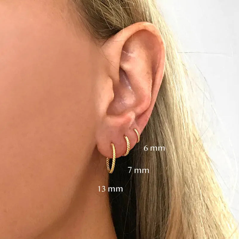 Close-up of a pair of twisted string round sterling silver earrings with gold plating.