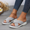Black women's wedge slippers with cross-strap and thick rubber sole, showing peep-toe design