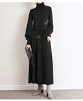 Adult lady wearing a solid colour knitted turtleneck dress with long sleeves, a loose mid-length skirt, and an elastic waist.