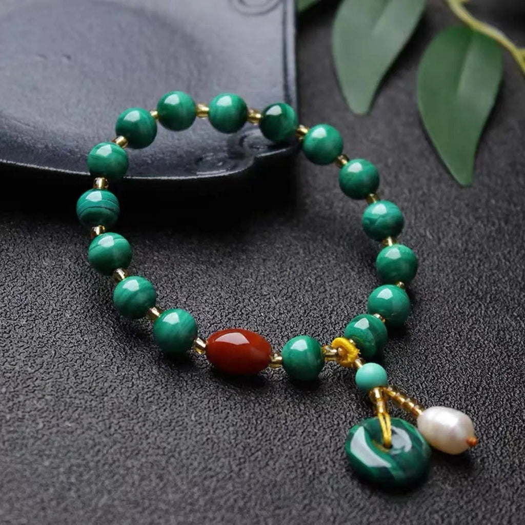 Natural malachite bracelet with green banded barrel beads on a neutral background