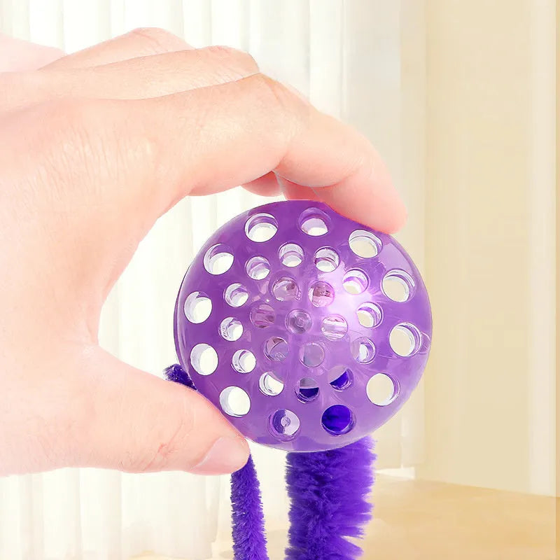 Interactive cat ball toy with plush tail in green, pink, and purple on white background