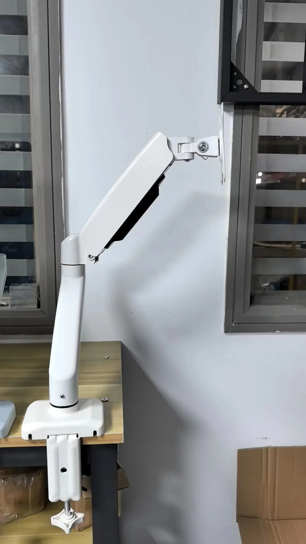 Black rotating telescopic LCD screen bracket on a desk showing height adjustment