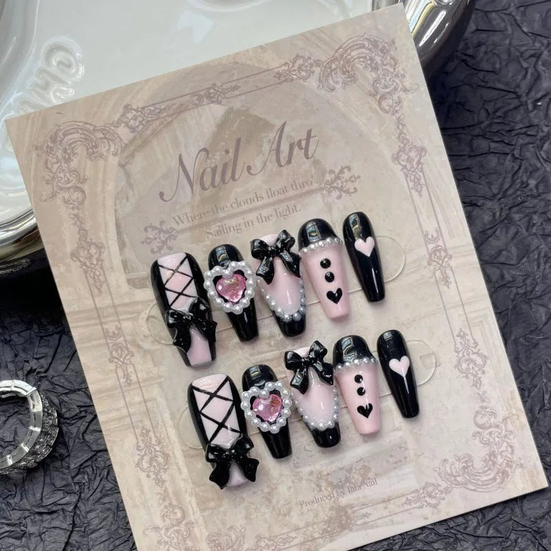 Black and pink heart-shaped handmade manicure set with bow pattern, shown in detachable plastic armour suit.