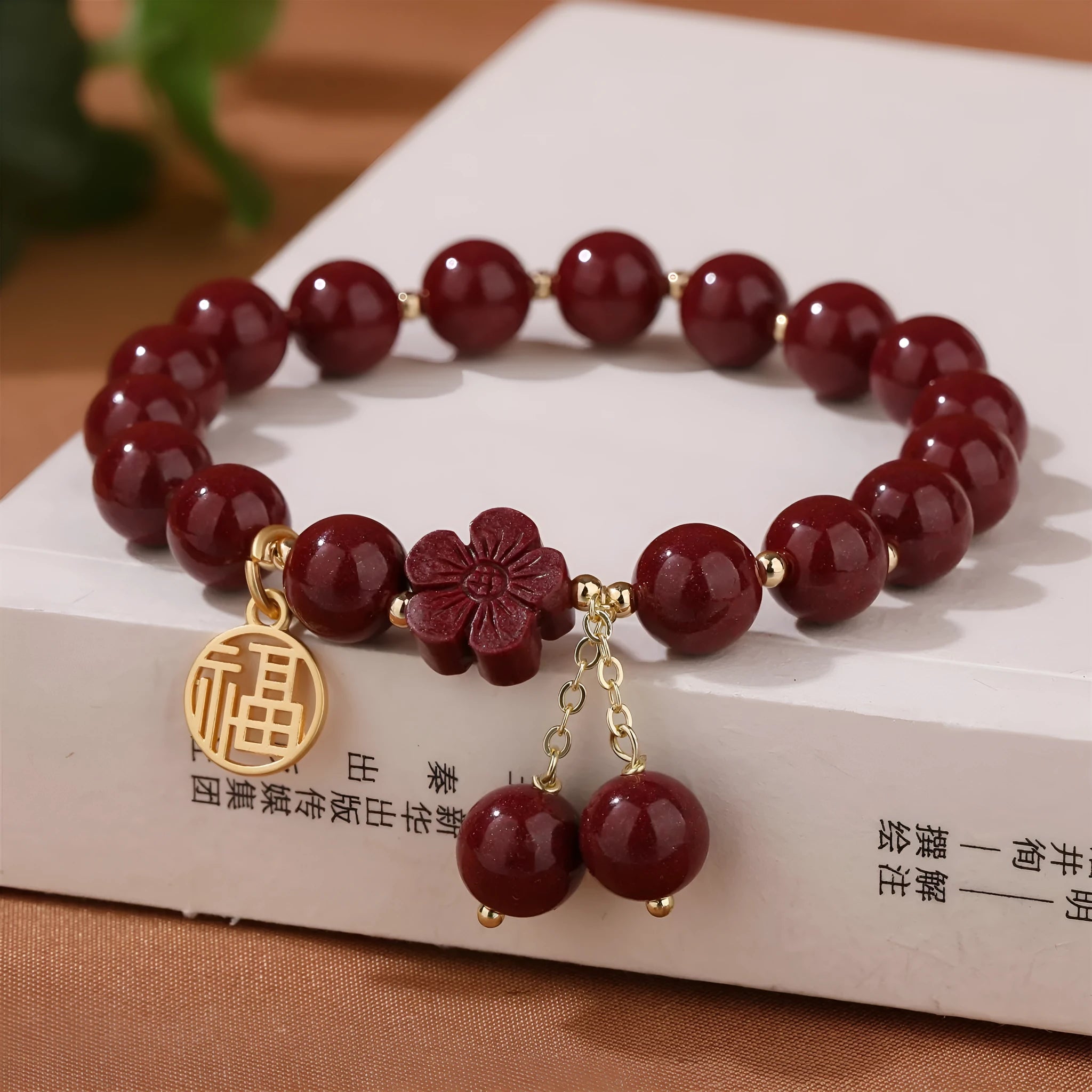 Handmade cinnabar bracelet with gold fu character and peach blossom tassel detail on white background